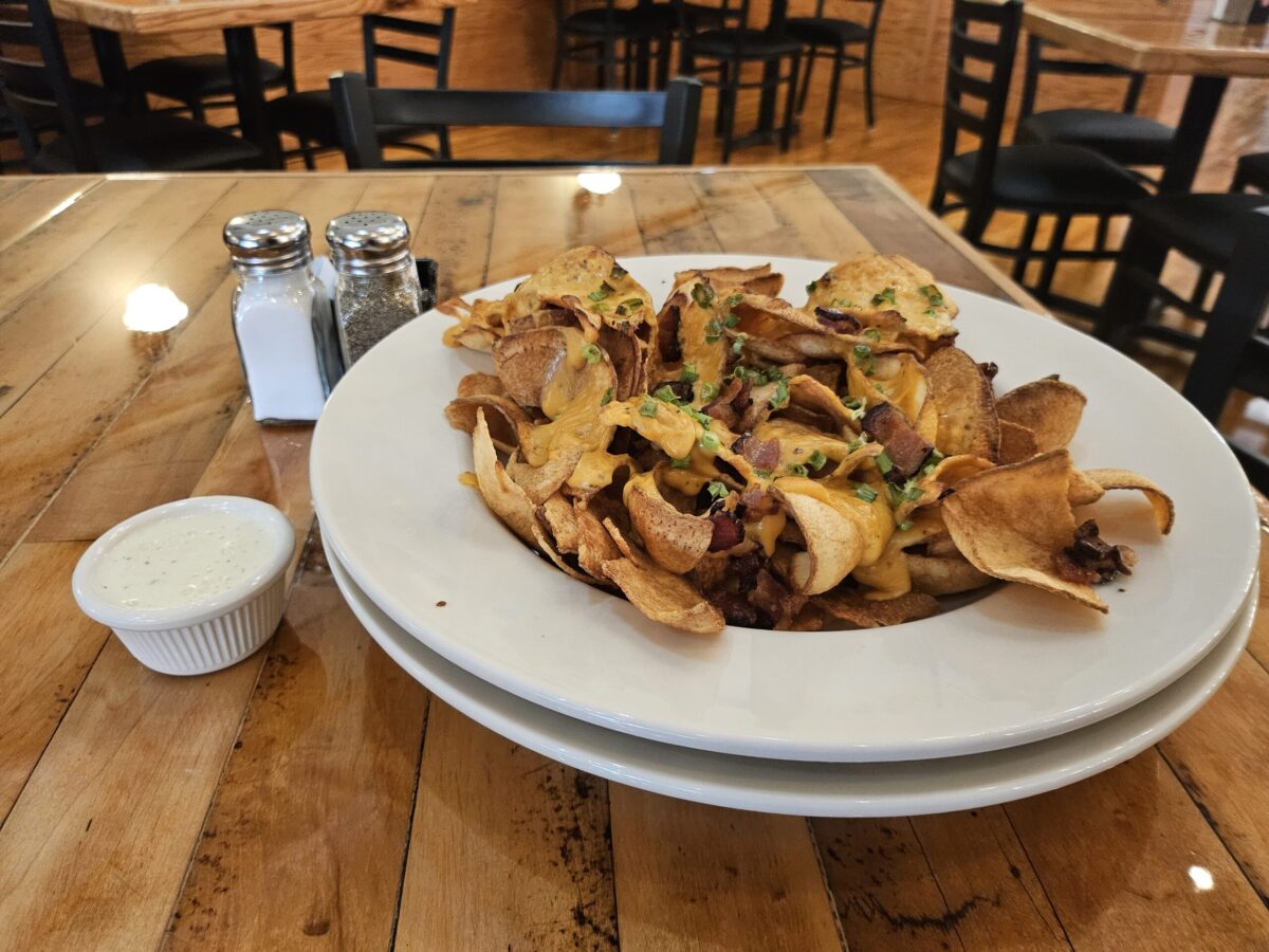 Loaded Tator Twister appetizer with hand-spiraled fried potatoes topped with bacon, cheddar cheese, jalapenos, and green onions, served with sour cream